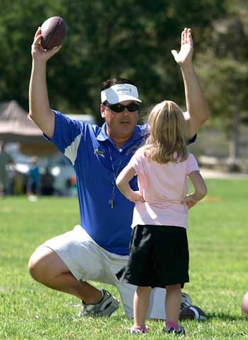 Supervisor Nelson holding a football in front of a little girl